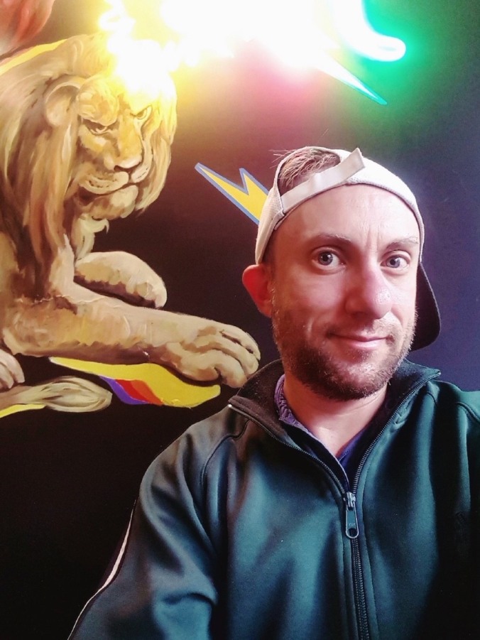 Tucker Lieberman in front of a painted mural of a lion with a Colombian flag